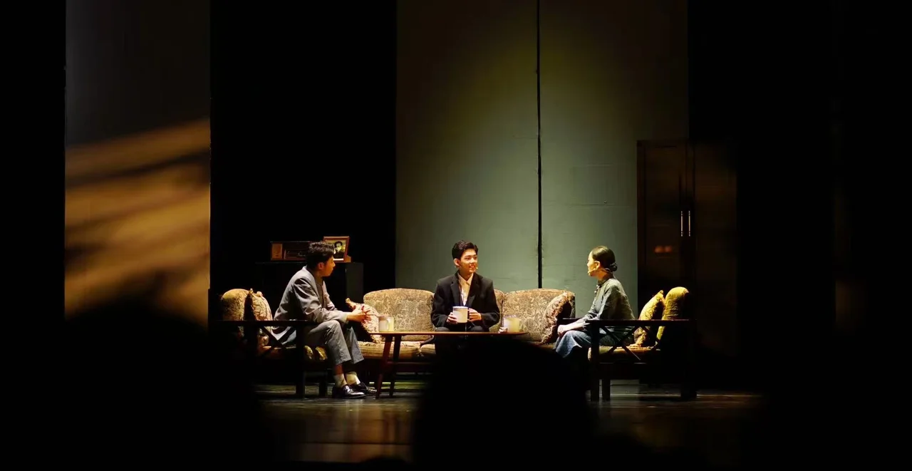 《寻找李白》舞台全景，三位演员围坐沙发与茶几旁，暖色灯光照在布景上