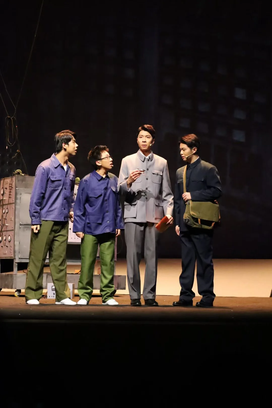 《与光同行》舞台上,四位演员围在一起,中央演员手持笔和红色本子