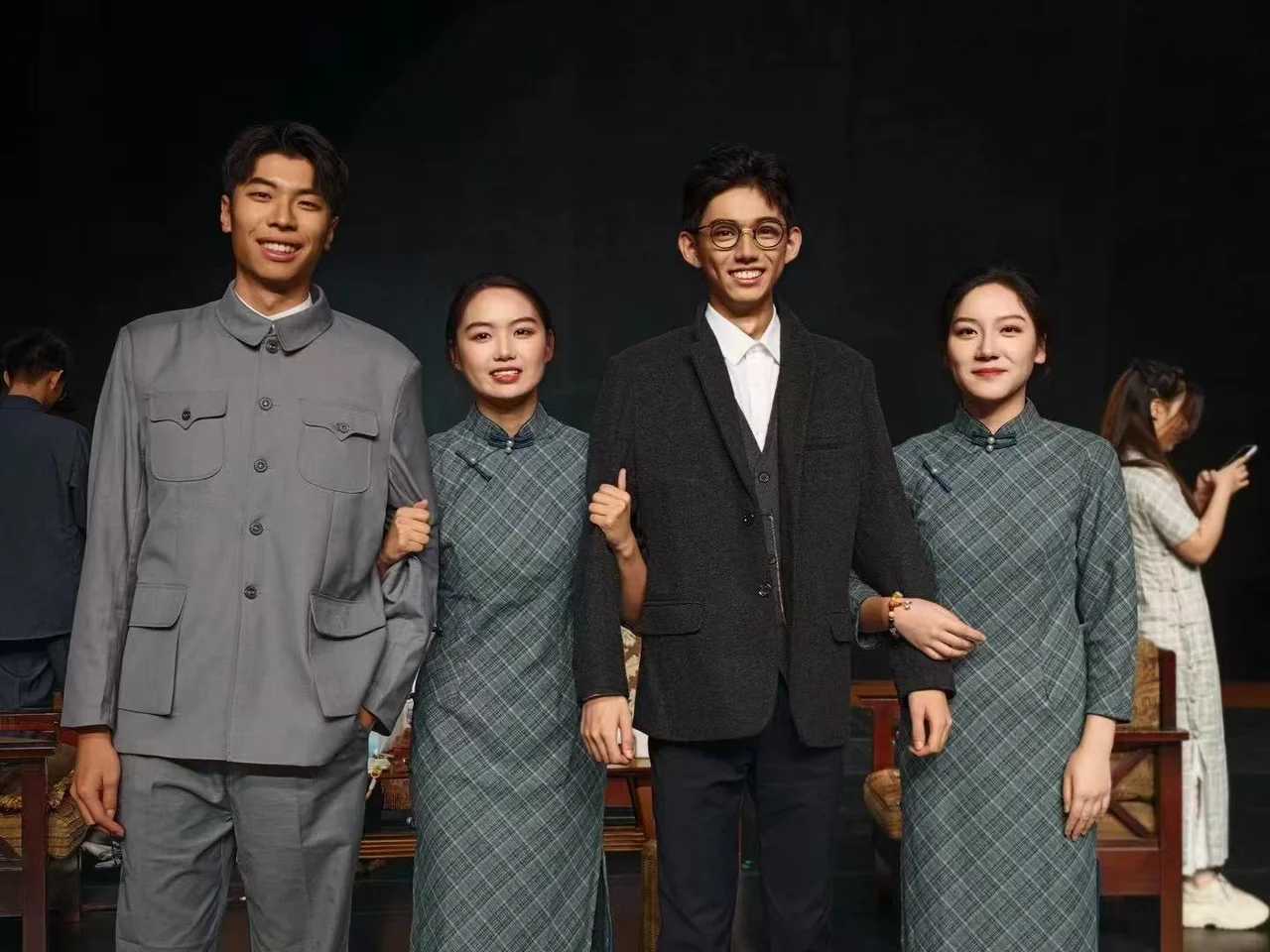 四位穿演出服的伙伴在舞台布景前微笑合影