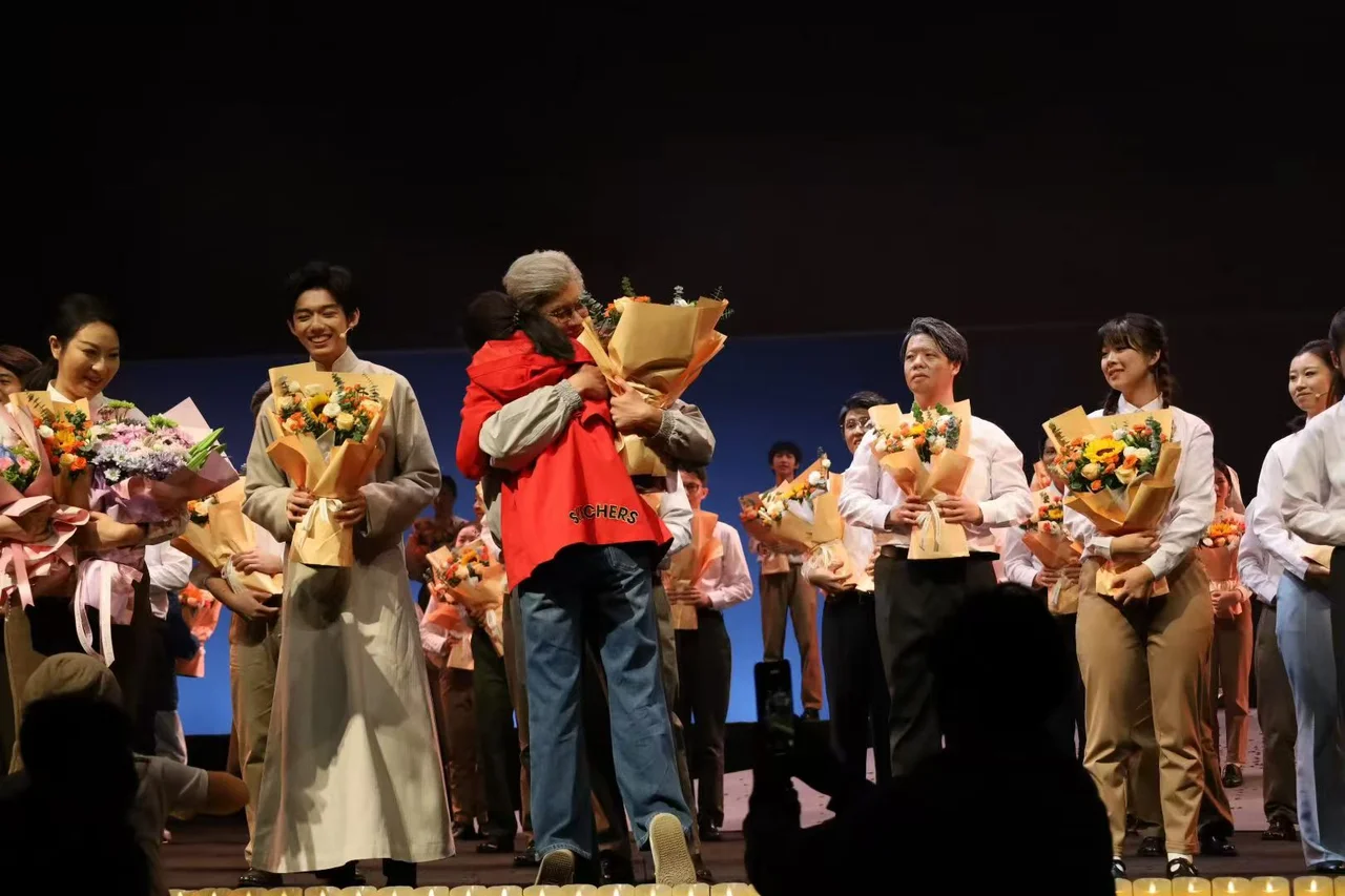 《与光同行》演出结束后,演员们手持鲜花,一位演员与送花的人拥抱