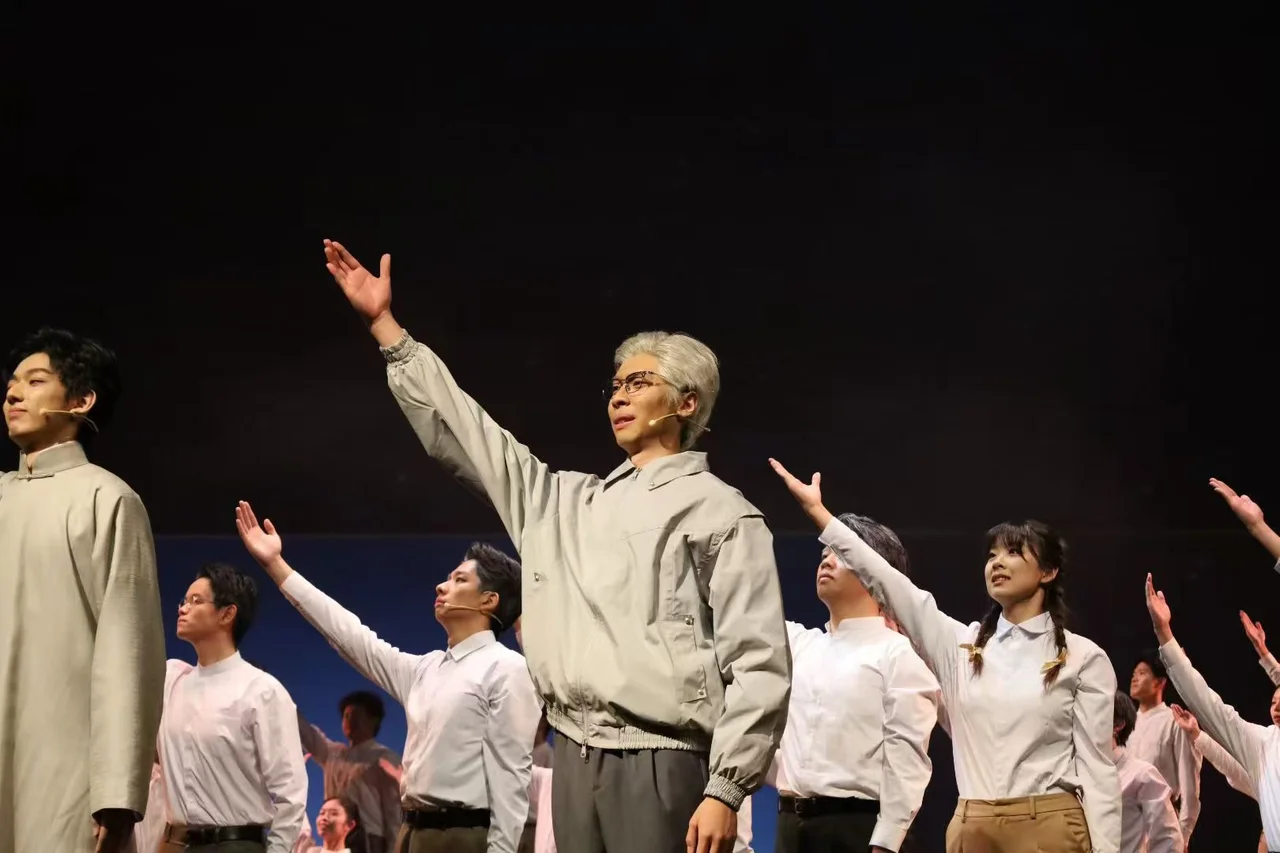 《与光同行》舞台上,灰发演员与其他演员一起举起手臂