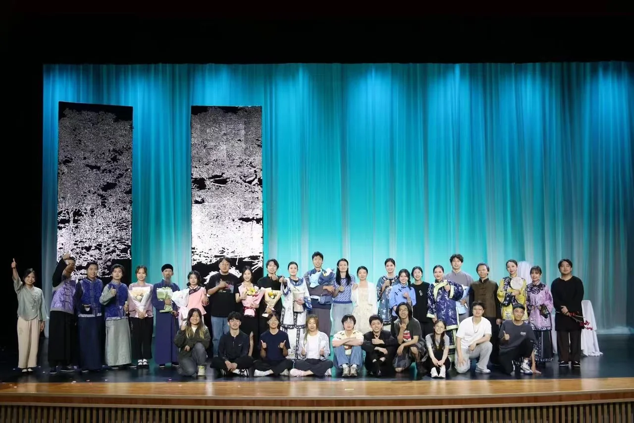 《家》的剧组在蓝色帷幕前合影，部分演员身穿演出服并手捧花束